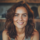 Femme souriante aux cheveux bruns ondulés.